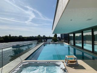 Moderne Terrasse mit Pool und Whirlpool, Blick auf den Fluss und den Himmel.